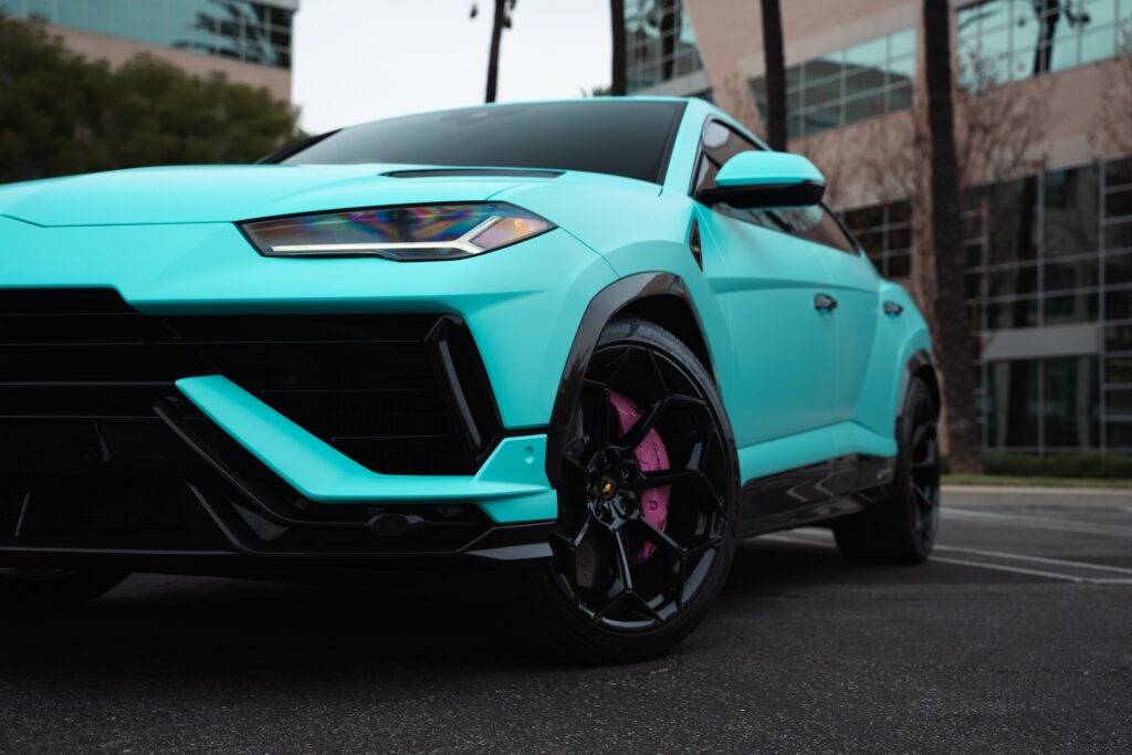 Blue Lamborghini Urus SUV parked outside modern office building.