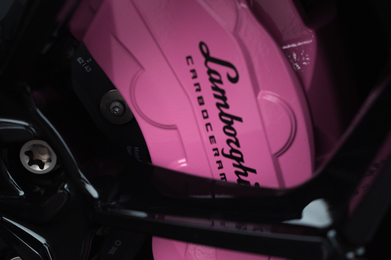 Close-up of pink Lamborghini brake caliper at The Auto Lounge gallery.