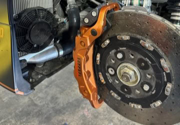 Brake system with orange caliper and ventilated disc.