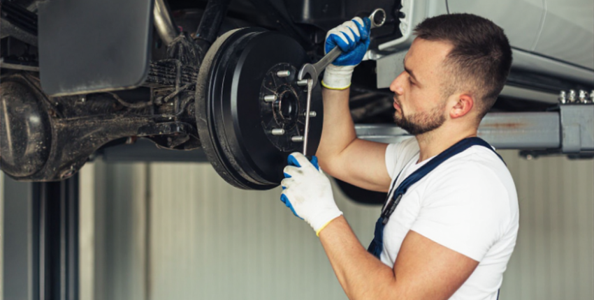 Mechanic inspecting car brake system for safety and maintenance.