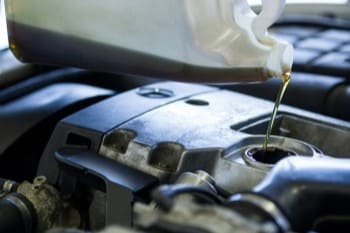 Engine oil being poured into a car engine during maintenance.