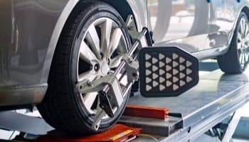 Wheel alignment equipment on a car's front wheel for precise adjustments.