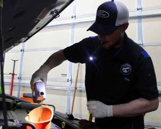 Automotive technician performing engine check in garage.
