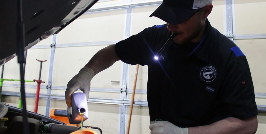 Automotive technician inspecting car engine in garage.