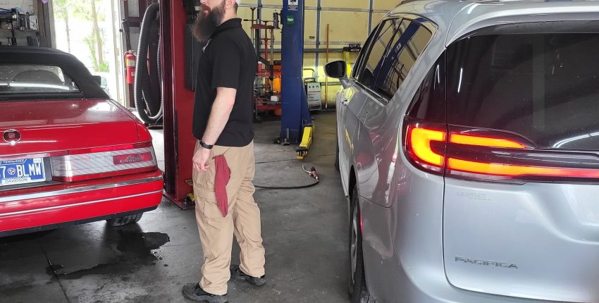 Technician inspecting a car in an auto repair shop for pre-purchase check.