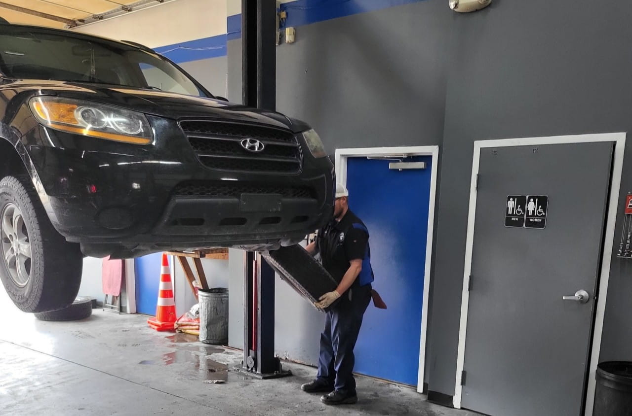 Black Hyundai SUV lifted for maintenance at The Car People auto shop.