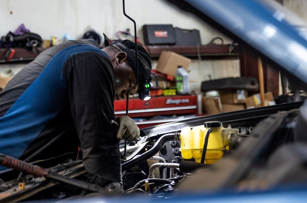 Mechanic working on car engine in auto repair shop.