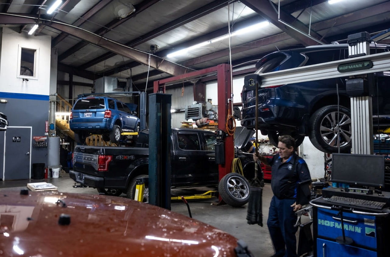 Auto repair shop with cars on lifts and mechanic working on vehicle.