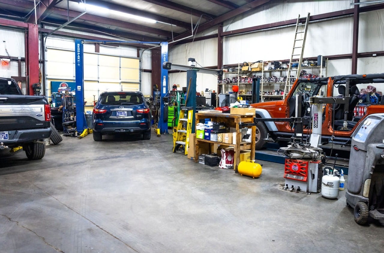 Inside a busy auto repair shop with vehicles and tools.