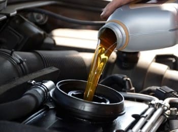 Engine oil being poured into a car engine during maintenance.