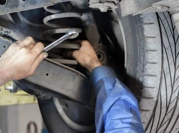 Auto repair technician inspecting and repairing a vehicle's suspension system.
