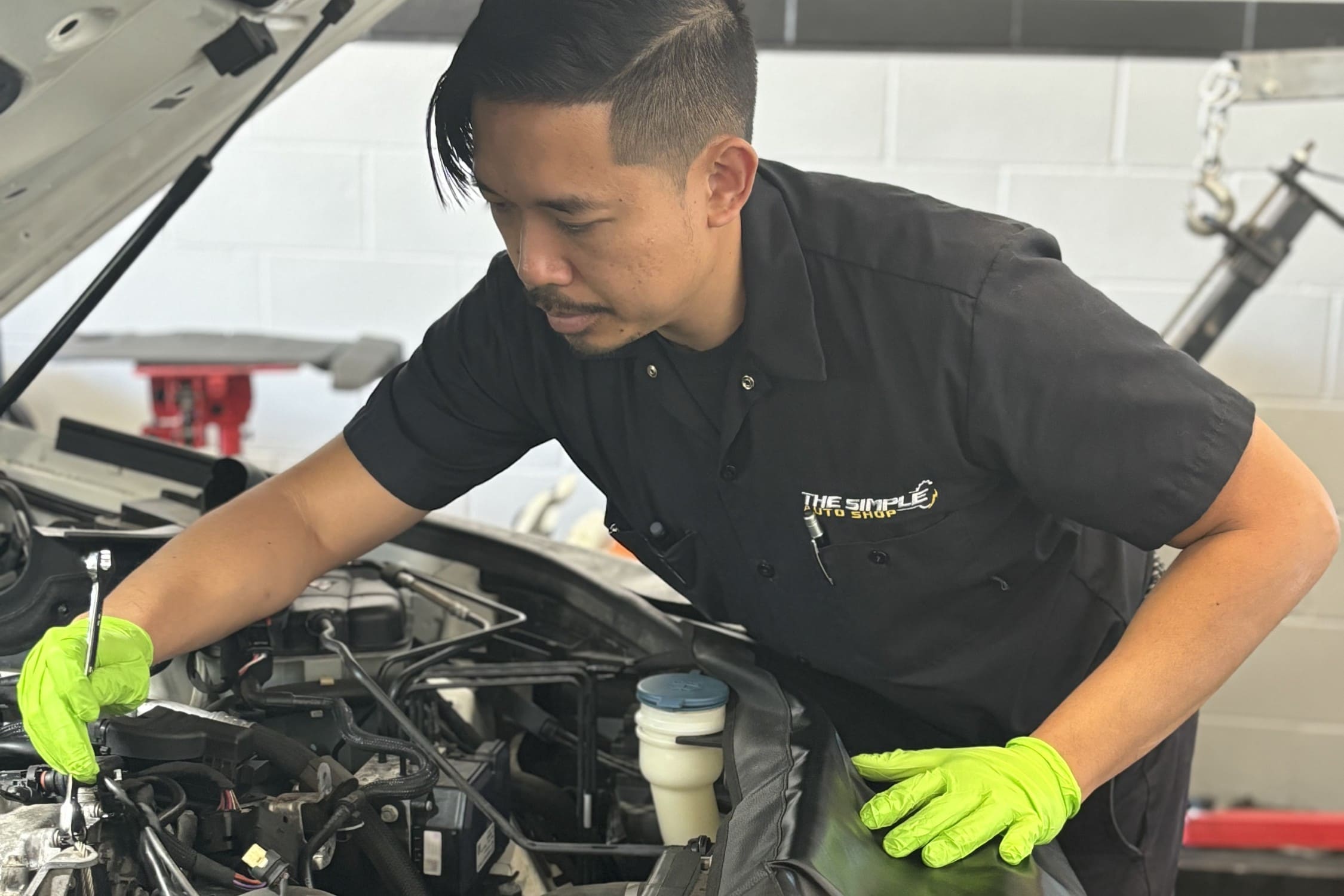 Engine repair technician inspecting a car engine with focus and precision.