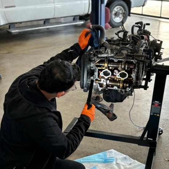 Engine repair technician working on a car engine in an auto shop.