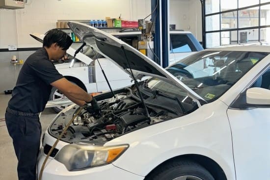 Auto repair technician inspecting a car engine in a professional garage.