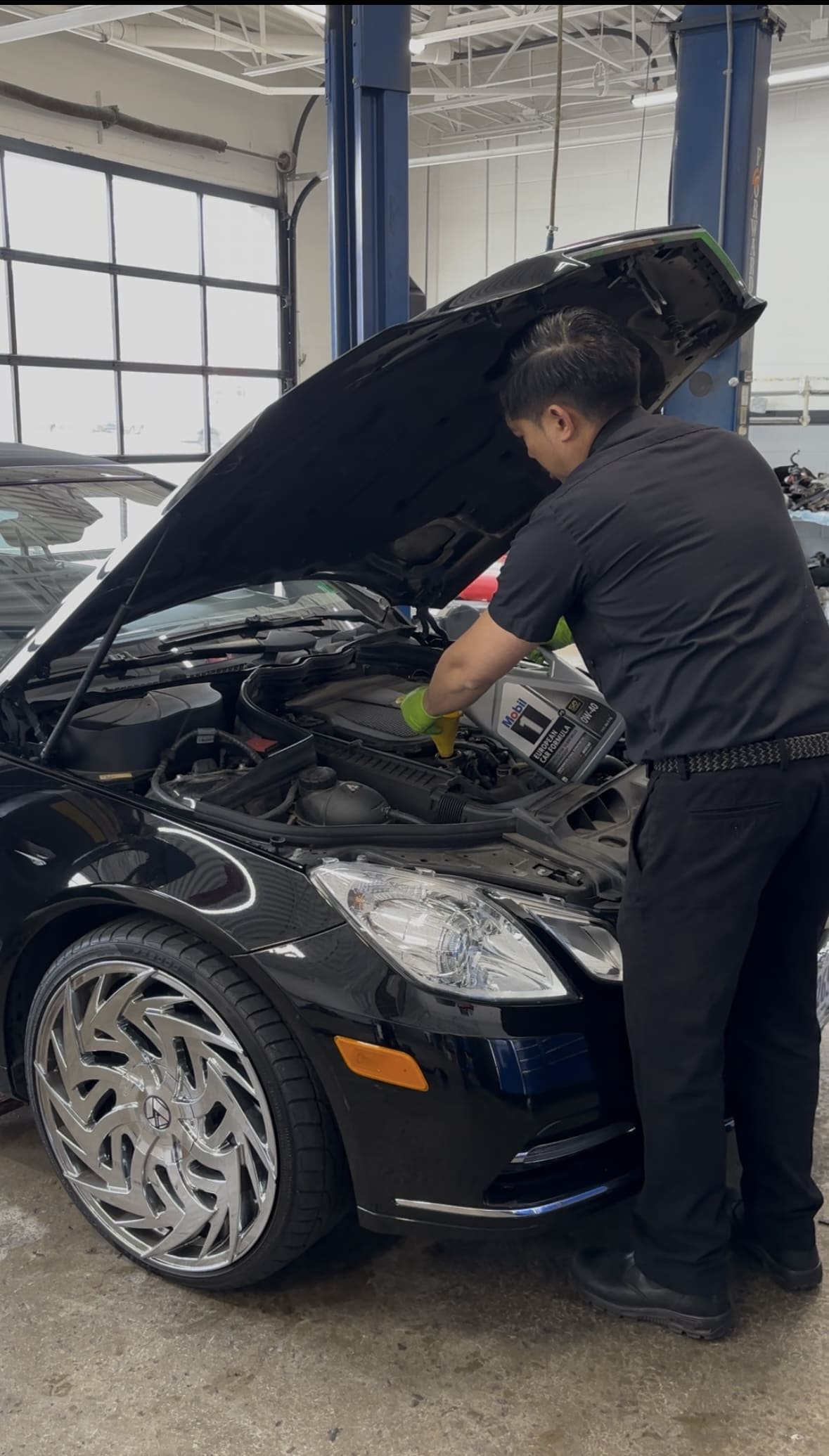 Auto mechanic inspecting car engine during maintenance service.