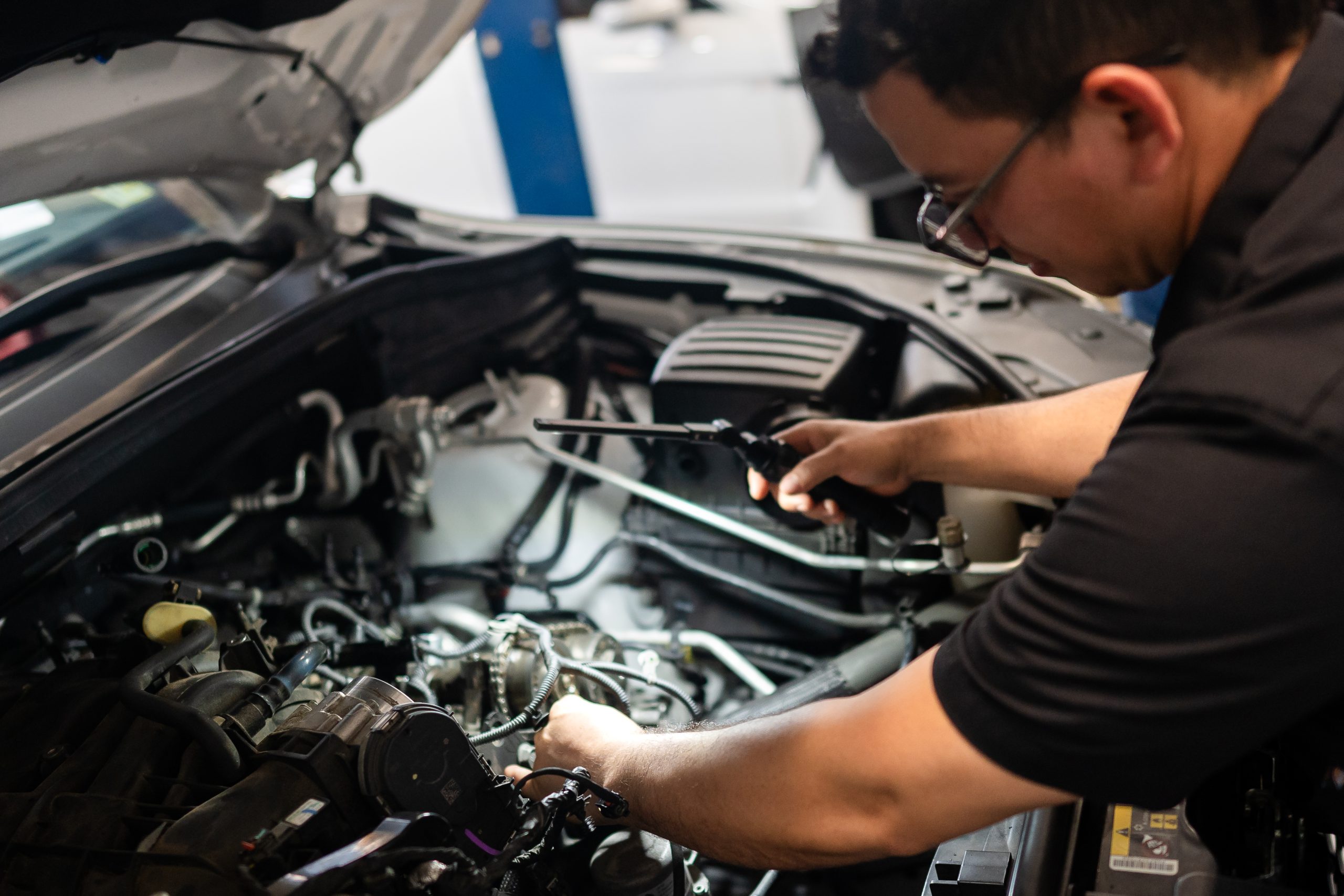 Mechanic inspecting car engine at The Simple Auto Shop.