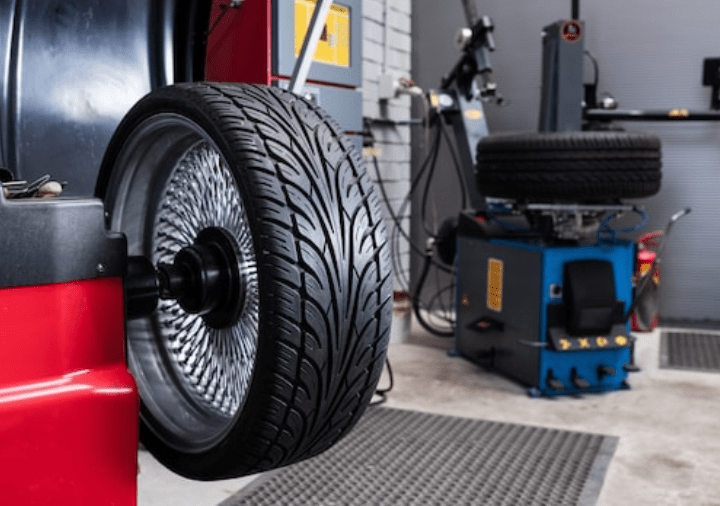Close-up of a car tire on a wheel balancing machine in an auto repair shop.