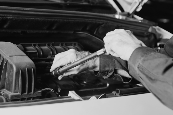 Engine repair technician inspecting car engine with tools for optimal performance.