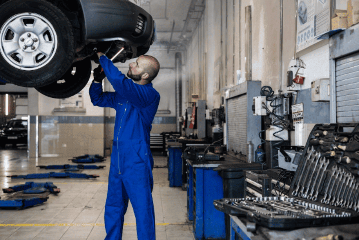 Brake repair technician inspecting vehicle undercarriage.