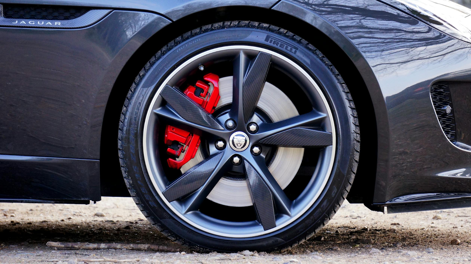 Close-up of Jaguar wheel with red brake calipers and performance tires.