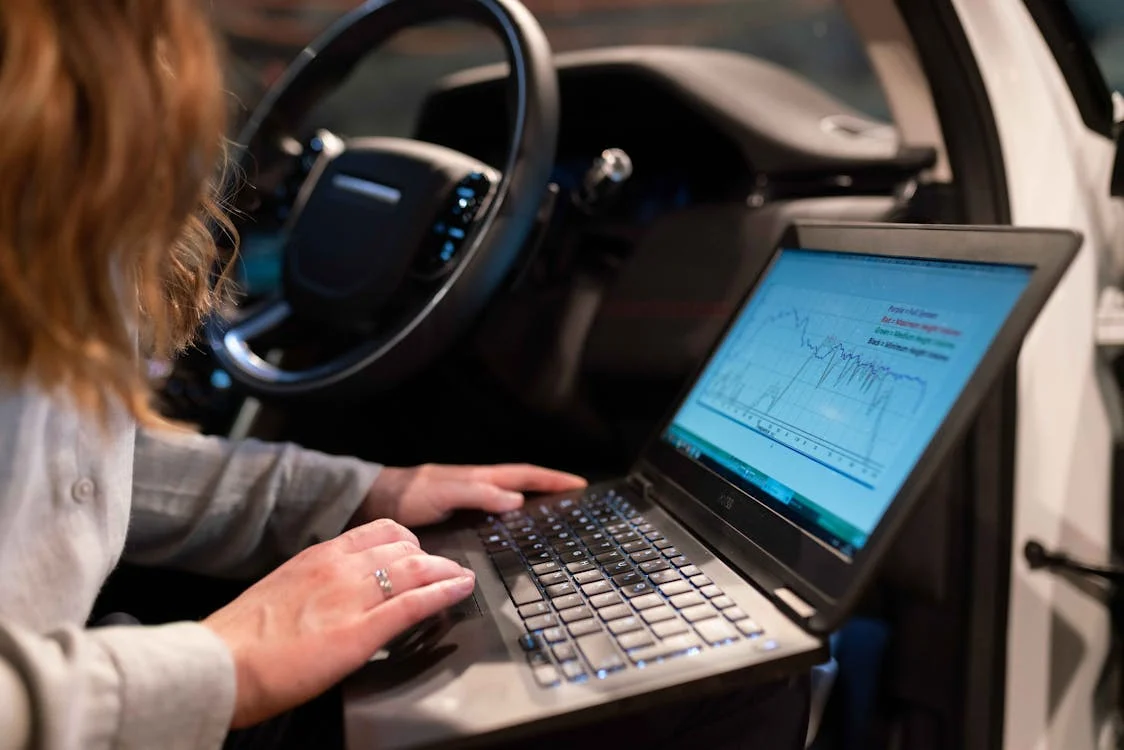 Auto diagnostics testing with a laptop inside a vehicle.