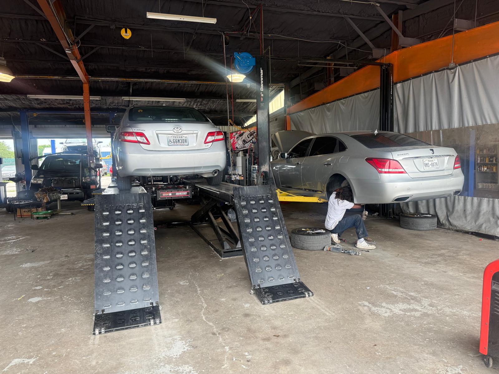 Auto repair shop with vehicle lifts and technicians working on cars.