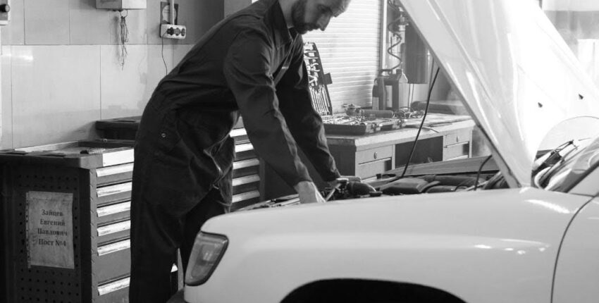 Skilled technician performing engine diagnostics on a vehicle in an auto repair shop.
