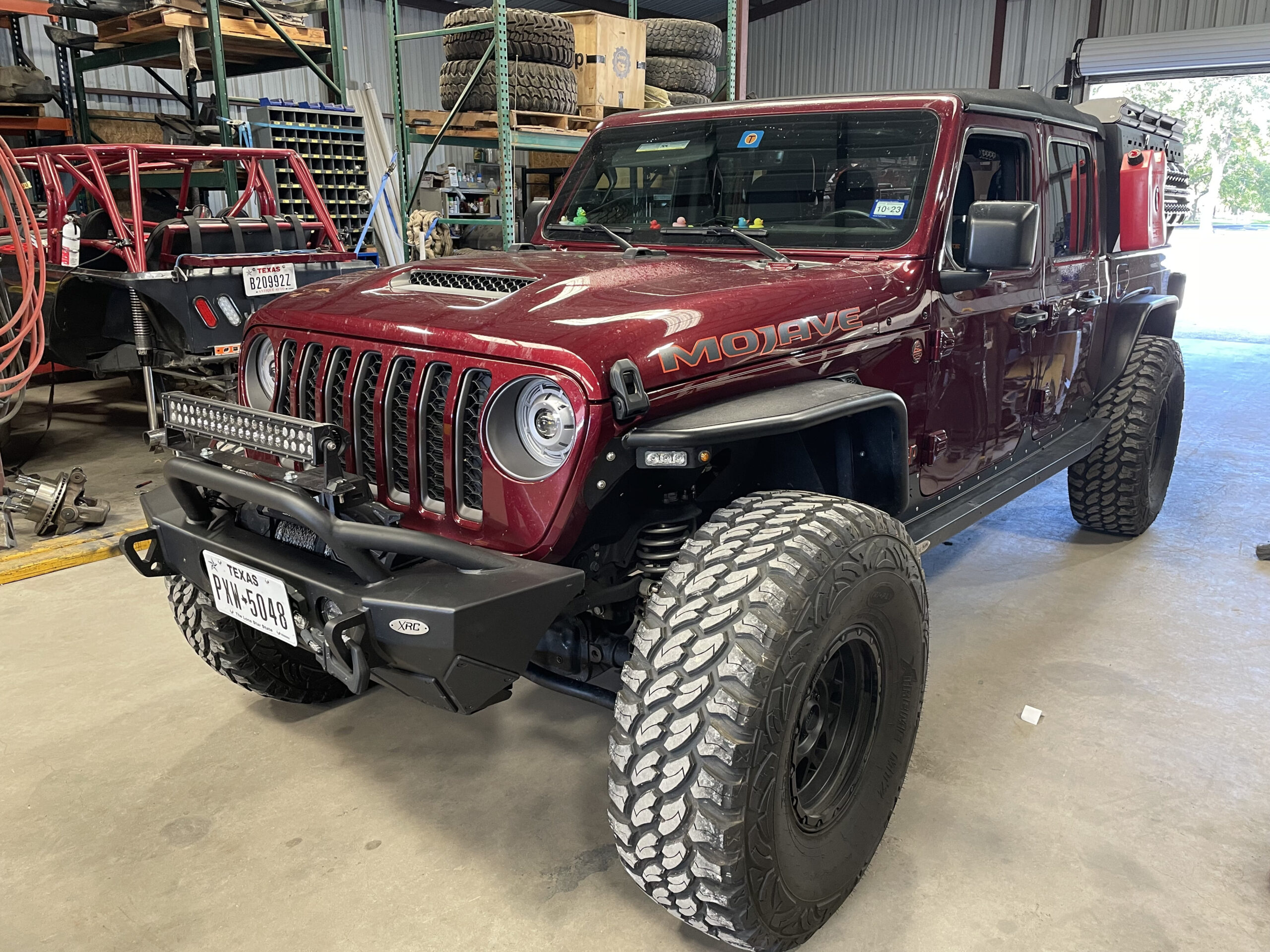 Custom off-road Jeep with large tires and upgraded bumper in workshop.