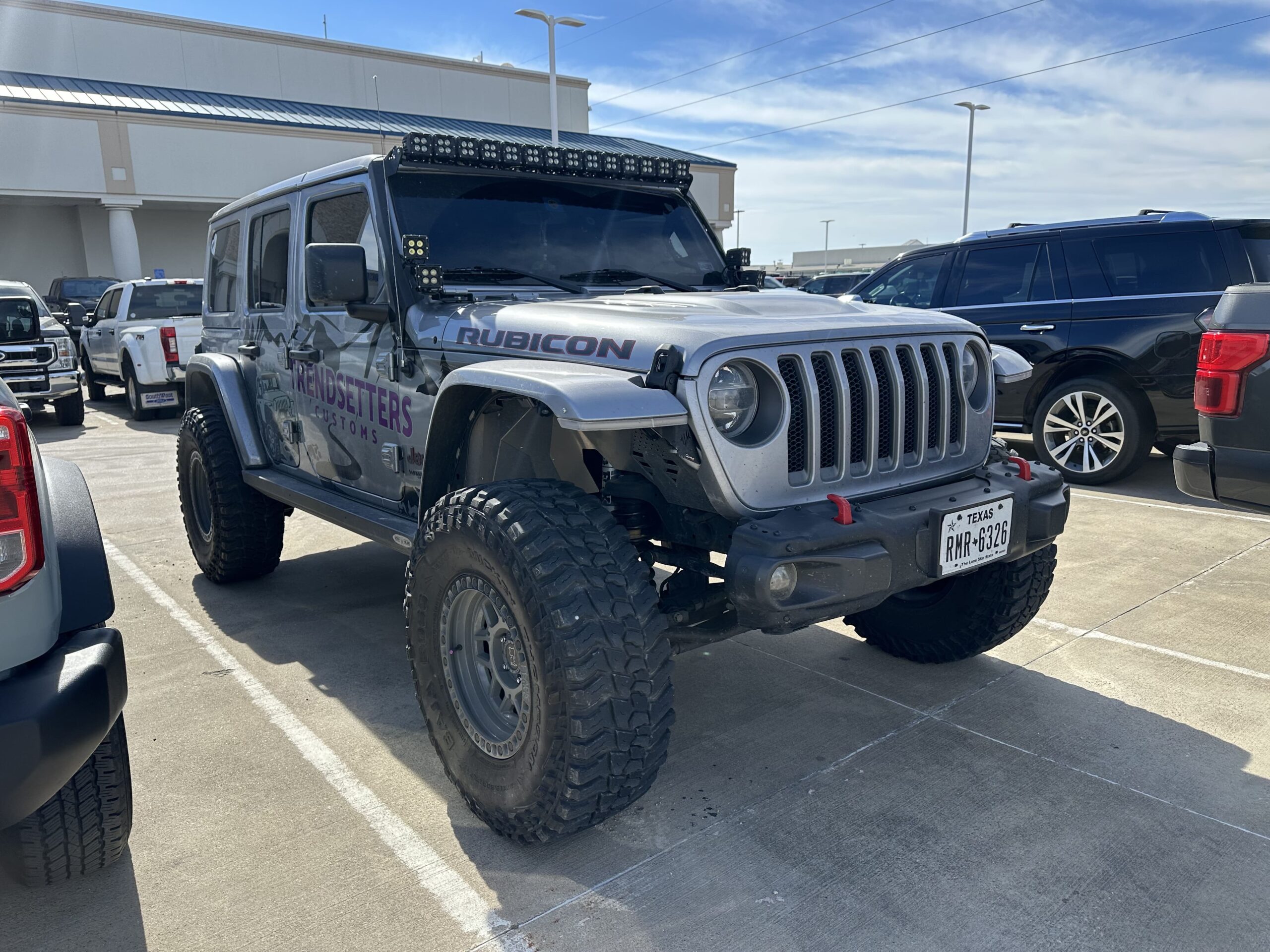 Jeep Wrangler Rubicon with custom off-road upgrades and accessories, parked in a dealership lot.