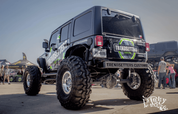 Custom off-road Jeep with lifted suspension and large tires at a car event.