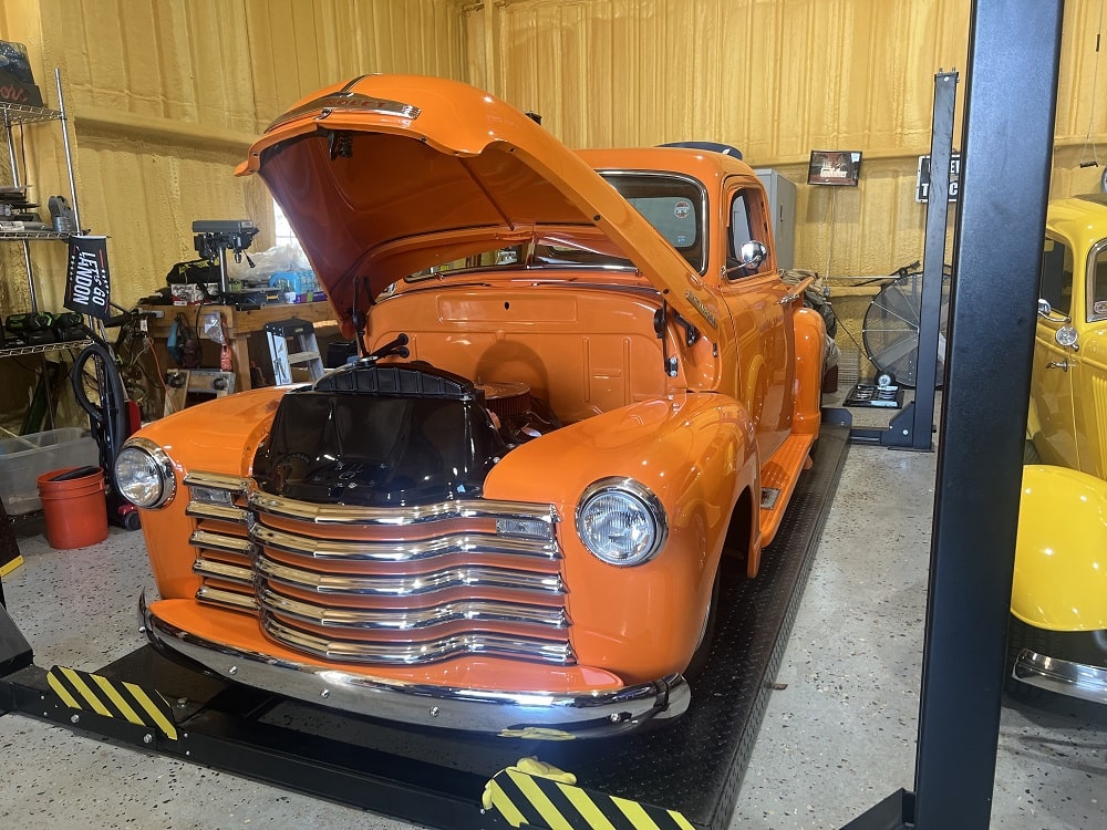 Orange vintage truck with custom paint and chrome details.