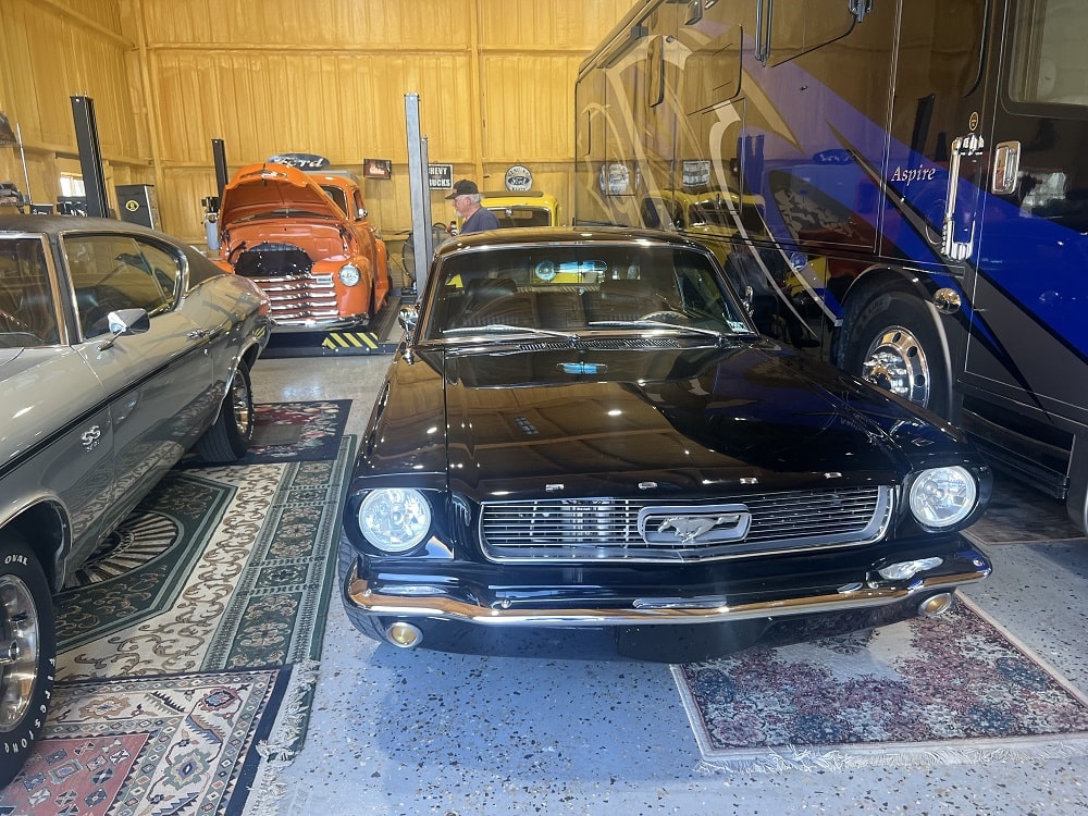 Vintage Ford Mustang in a classic car showroom with other collectible vehicles.