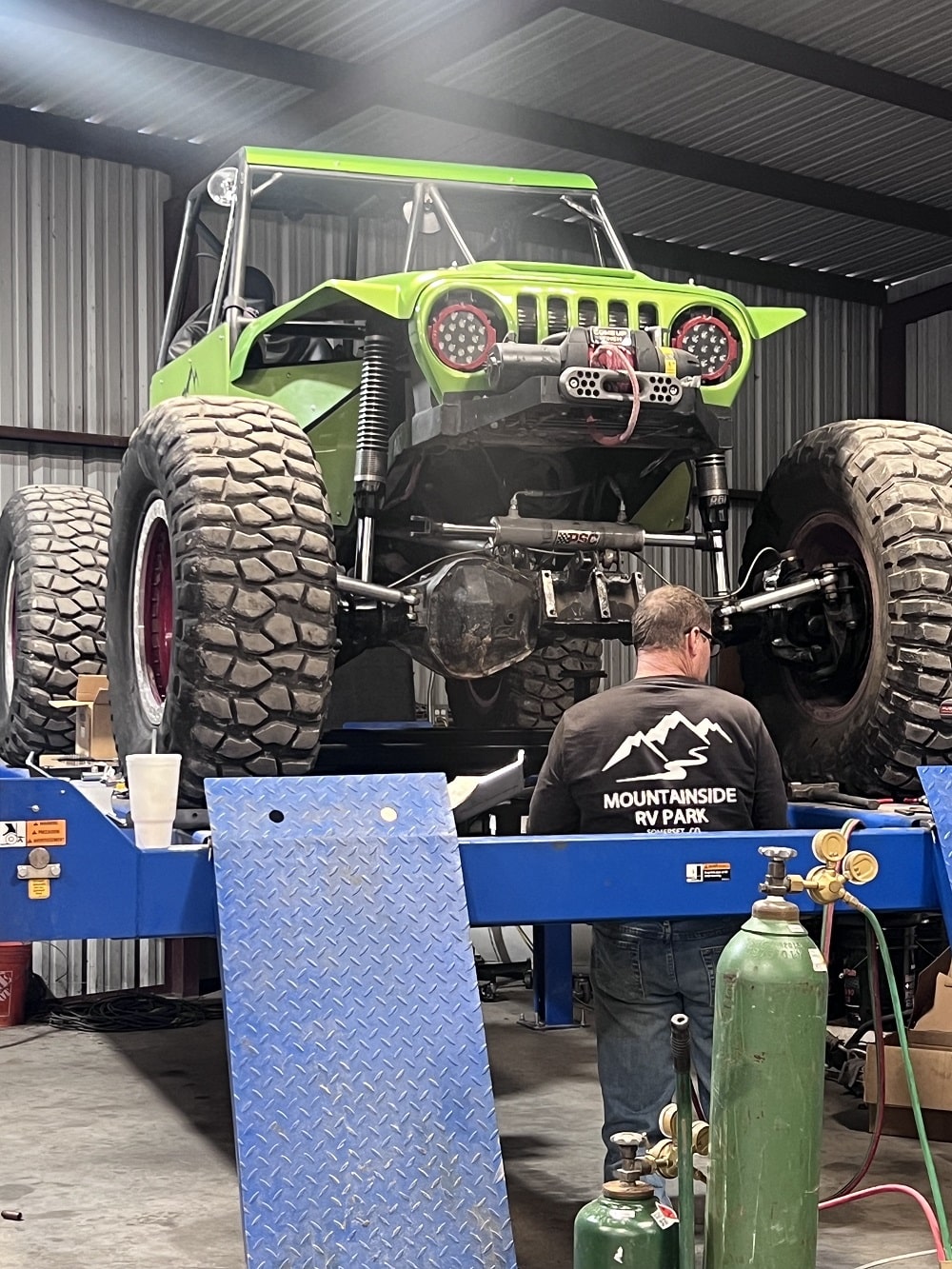 Off-road vehicle with custom green paint and large tires on a lift.