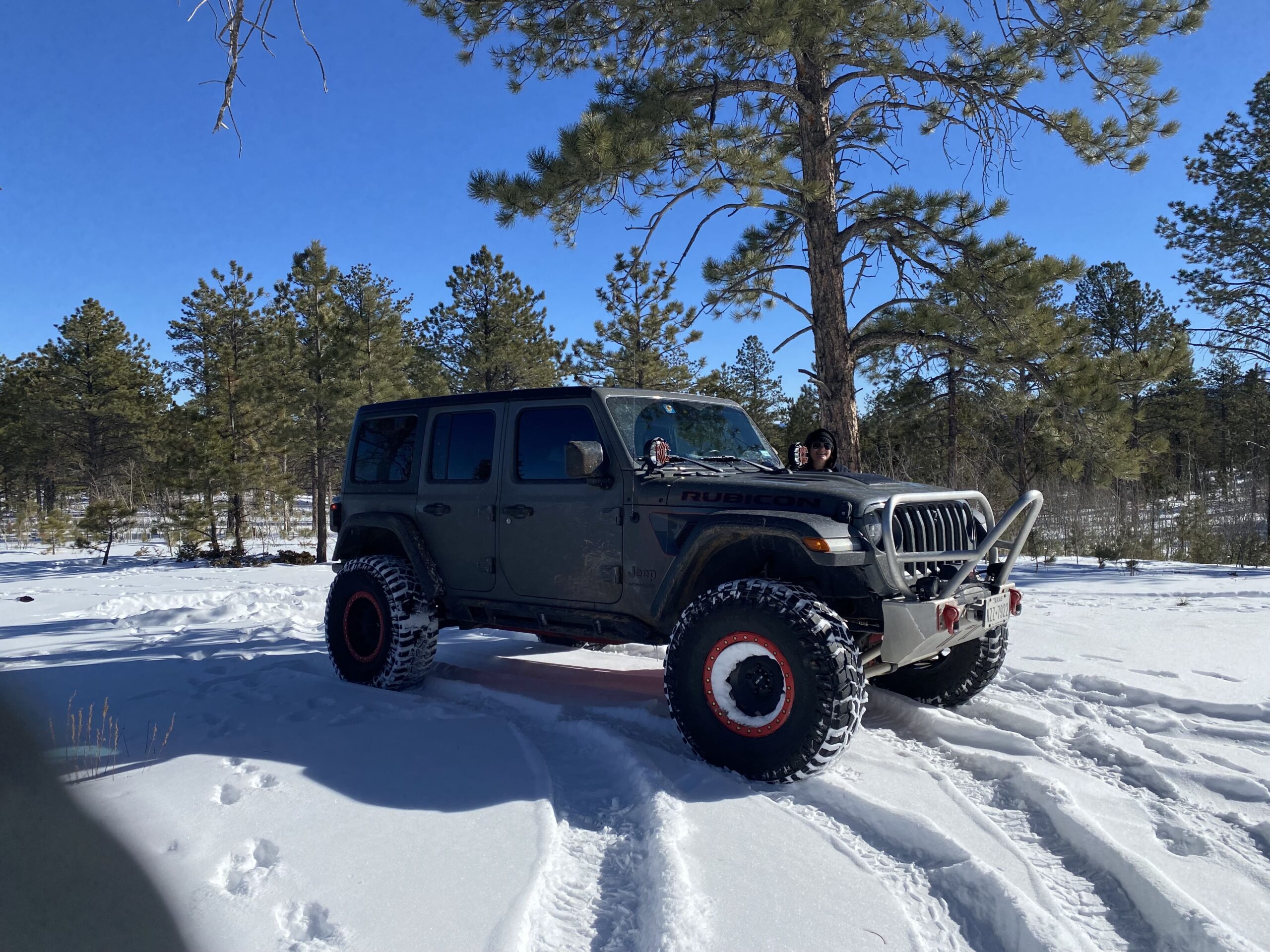 Off-road Jeep Wrangler with custom modifications in snowy landscape.