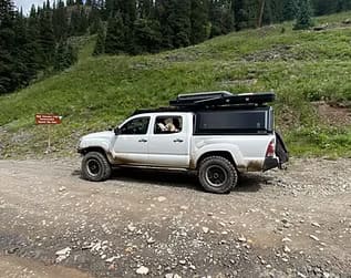 Truck with custom roof rack and off-road accessories in a mountainous terrain.