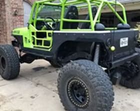 Off-road custom vehicle with green roll cage and rugged tires.