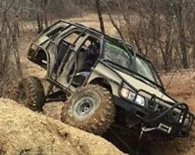Off-road Jeep climbing rocky terrain with rugged tires and suspension.