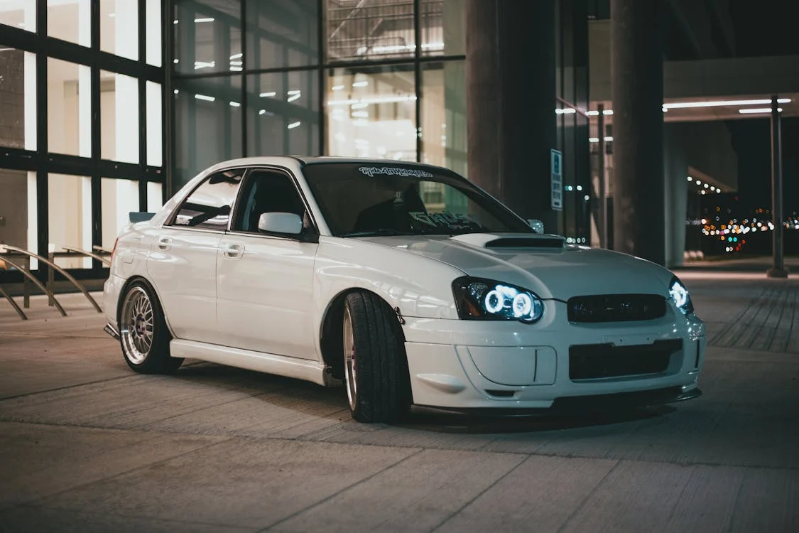 White modified car with off-road suspension and wheels for rugged terrain.