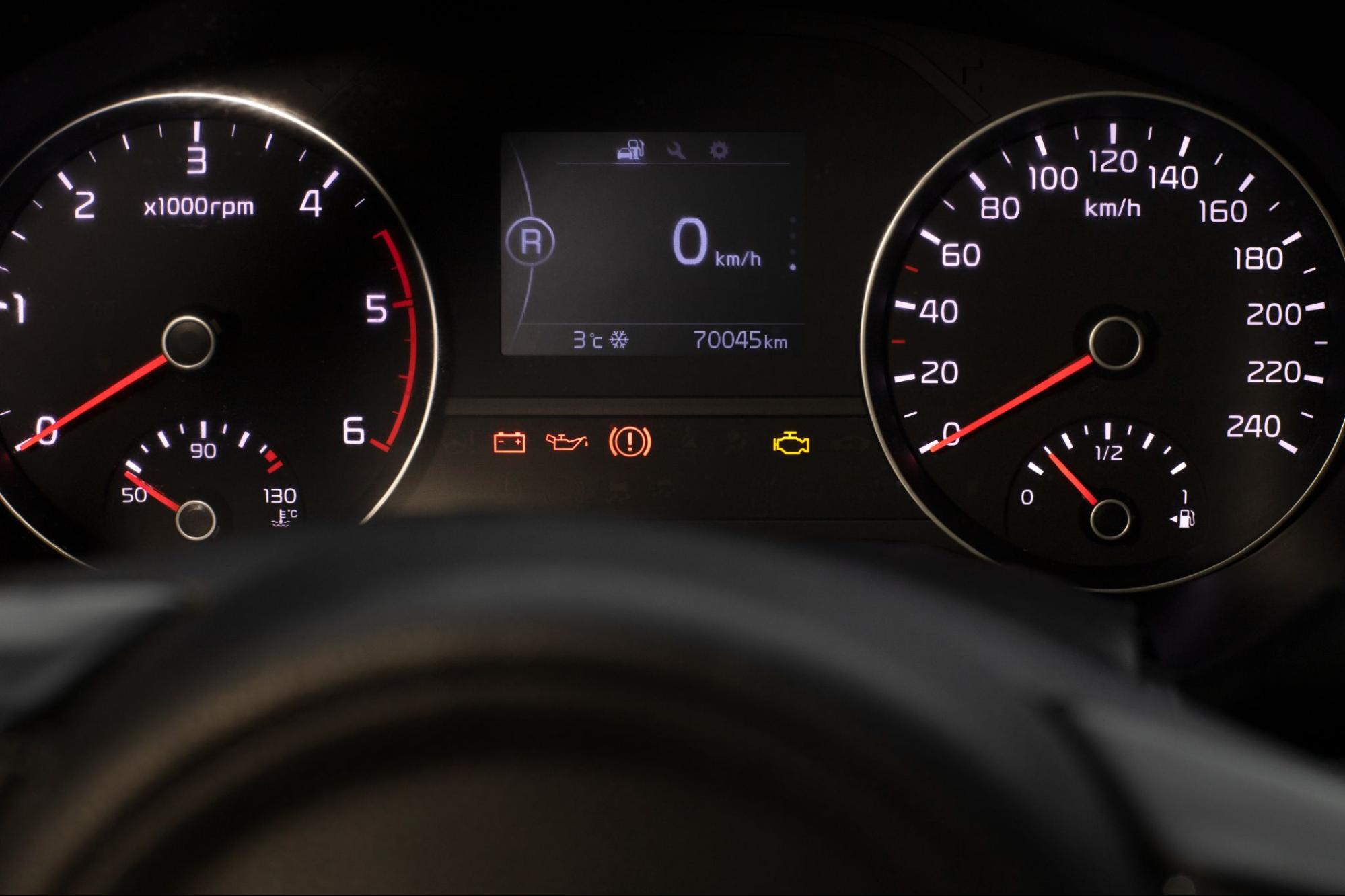 Car dashboard with check engine light indicator and speedometer.