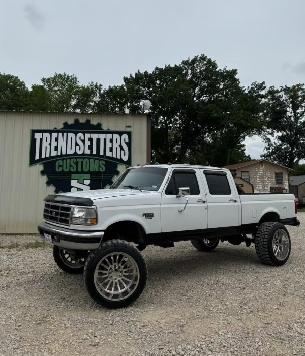 White lifted truck with large wheels parked outside Trendsetters Customs.