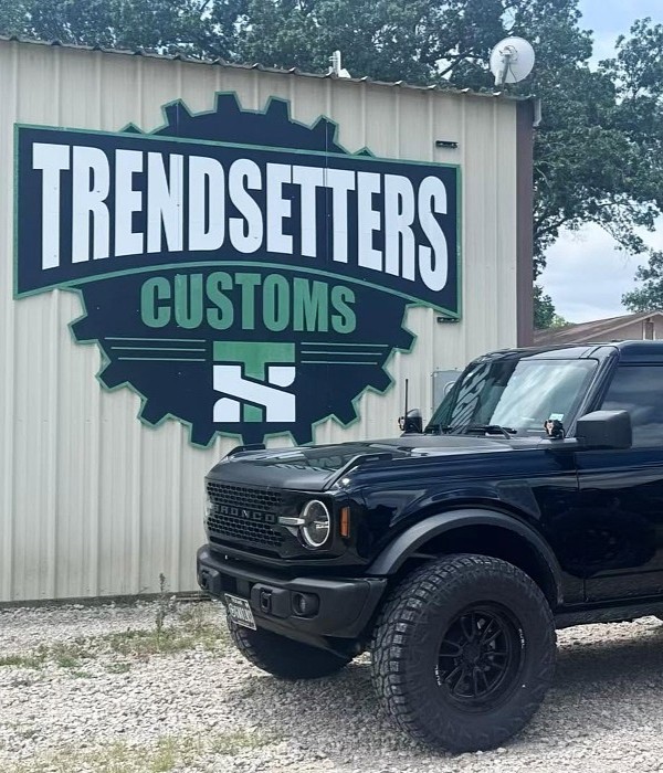 Black off-road vehicle parked near Trendsetters Customs sign.