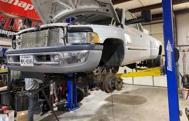 White luxury car on lift undergoing restoration at Trendsetters Customs.
