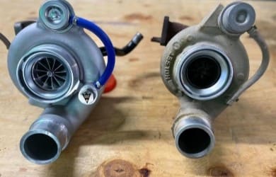 Two turbochargers on a wooden surface, showcasing automotive performance parts.