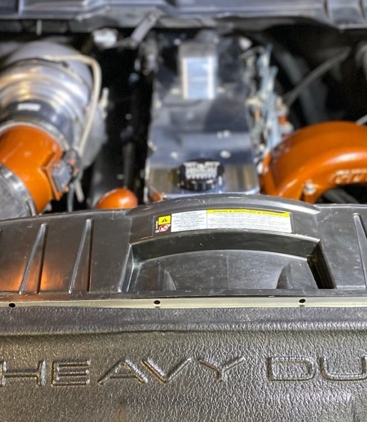 Close-up of a customized engine bay with orange accents and performance parts.