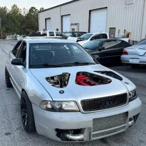 Modified Audi sedan with performance upgrades and custom hood in a workshop setting.