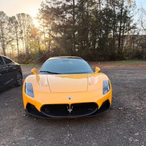 Yellow Maserati supercar parked outdoors at sunset, showcasing luxury and performance.