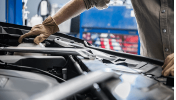 Skilled mechanic inspecting car engine during auto repair service.