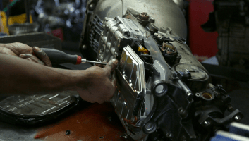 Mechanic repairing a car engine with tools at Uncle D’s Auto Repair shop.