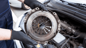 Technician inspecting a car clutch plate during transmission repair at Uncle D’s.