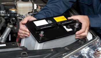 Technician replacing car battery at Universal Tire Tire Center.